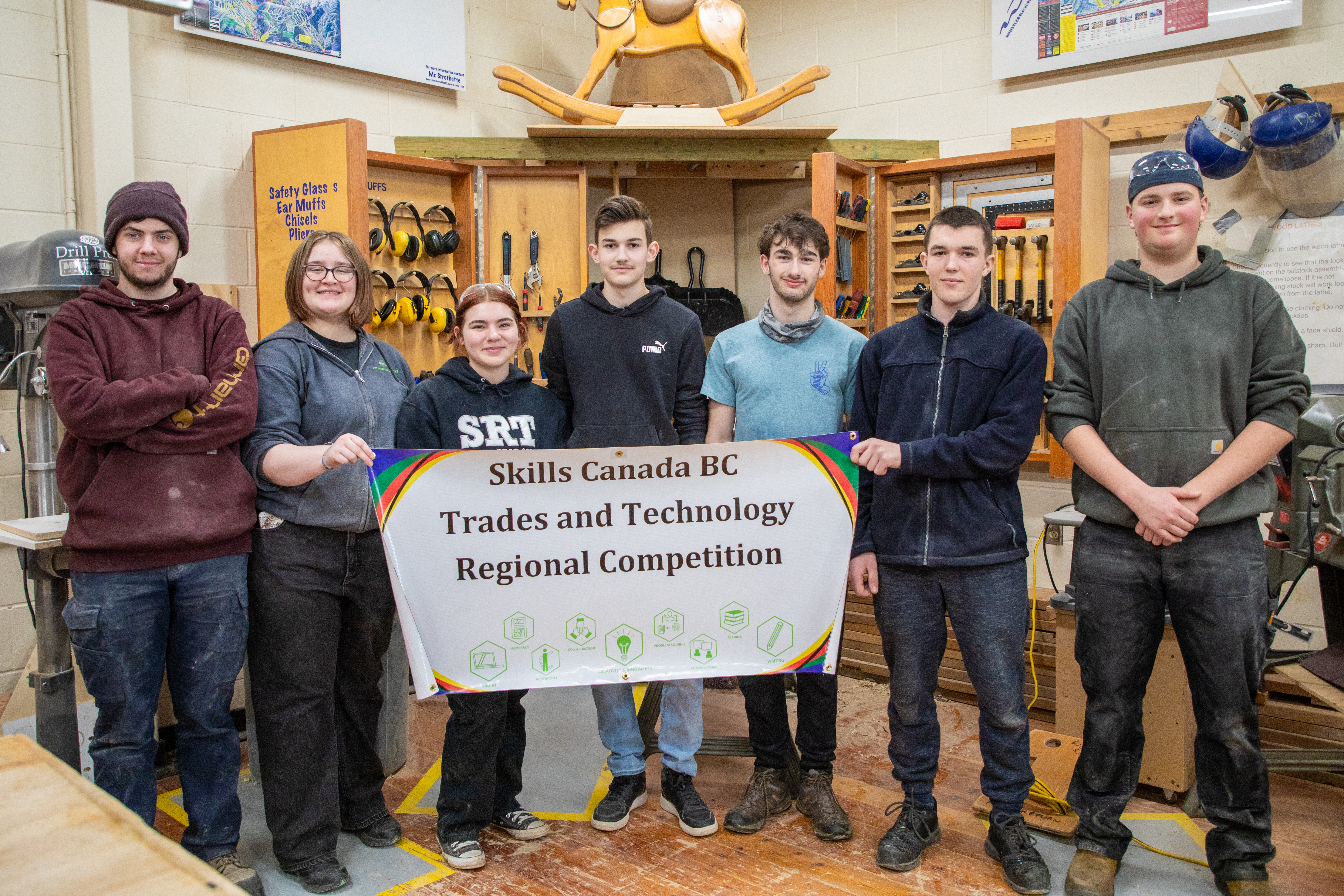 Students who participated in the Skills Canada BC cabinetmaking regional competition hold up a sign with the competition name.